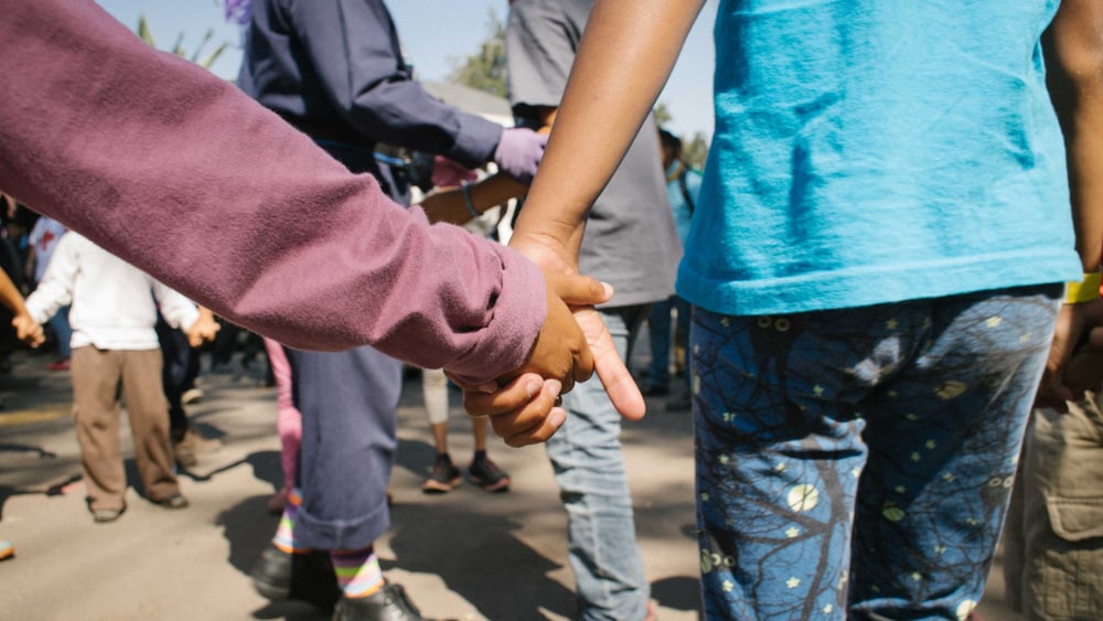 Due bambini visti da dietro che si tengono per mano.