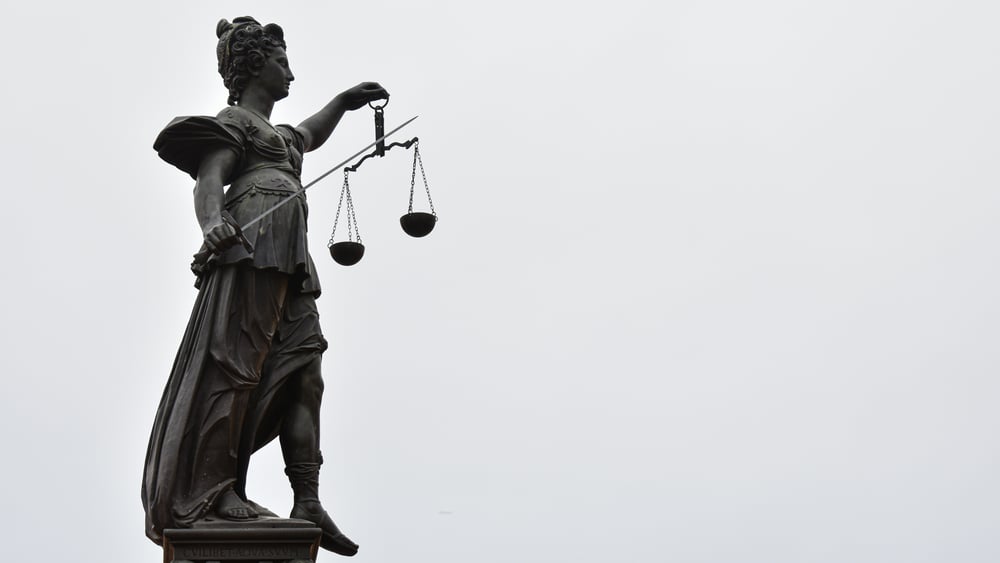 Immagine di una statua della Giustizia, con la spada, la bilancia e la benda.