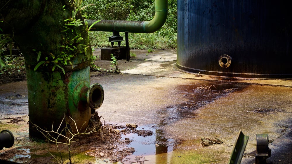 Tubi che spuntano dal terreno, un grosso barile con un'apertura e chiazze di petrolio sul pavimento. Tutto questo nel bel mezzo della giungla.