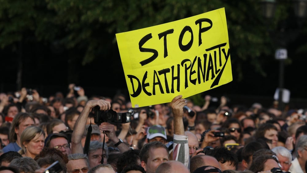 Un manifestante chiede la fine della pena di morte con un cartello su cui è scritto «Stop Death Penalty».