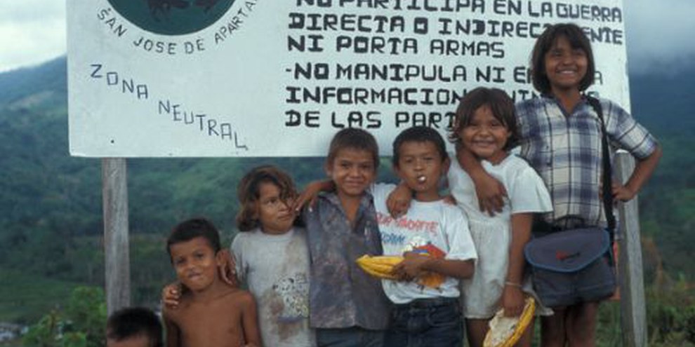 Kinder der Gemeinde San José de Apartado stehen vor einem Schild das auf die neutrale Zone hinweist. © privat