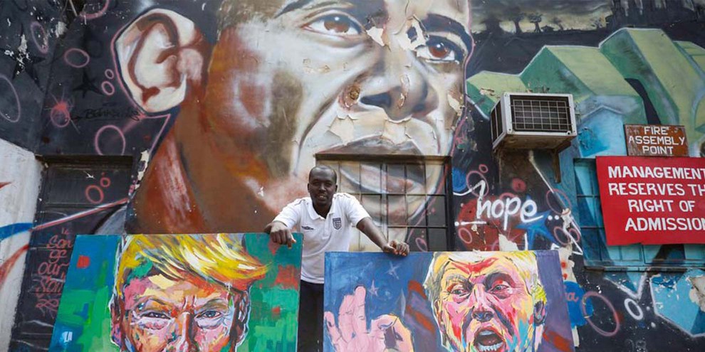 Der kenianische Künstler 'Yegonizer' mit seinen Bildern von Trump vor einem Obama-Wandbild des Künstlers Bankslave. © Keystone/EPA/DAI KUROKAWA
