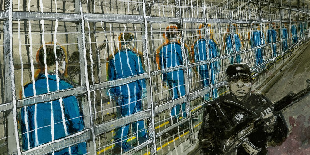 Häftlinge, die durch einen engen umzäunten Bereich – im Grunde ein Käfig – zu dem Gebäude zu gehen, in dem sich ihre «Klassenräume» befinden.© Molly Crabapple