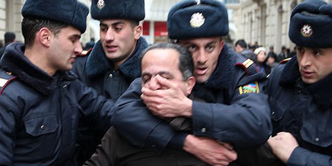Polizisten bringen einen Aktivisten zum Verstummen. Baku, 12. März 2011. © AI