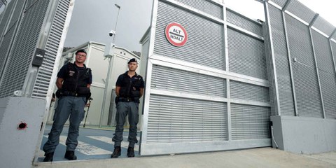 Italienische Polizisten stehen am 11. Oktober 2024 am Eingang eines kürzlich errichteten, von Italien betriebenen Migrant*innenzentrums im Hafen von Shengjin, etwa 60 Kilometer nordwestlich von Tirana © ADNAN BECI/AFP via Getty Images