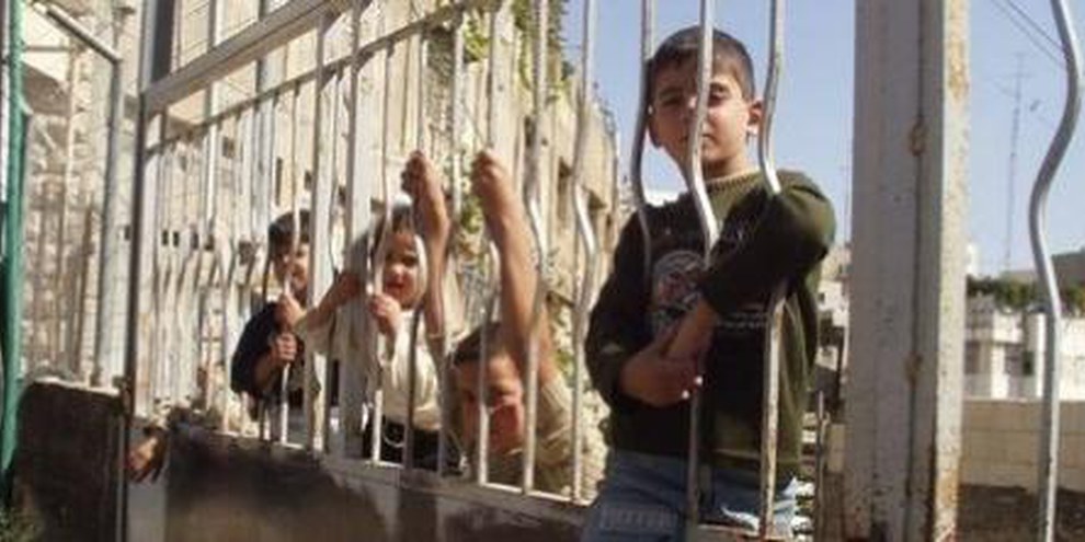Palästinensische Kinder sitzen auf der Absperrung eines Checkpoints, der ihren Schulweg versperrt © CPT