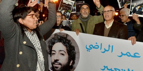 Demonstrant*innen am 28. Dezember 2019 in Rabat, die ein Transparent hochhalten, das den Journalisten Omar Radi zeigt. Er wurde wegen eines Tweets inhaftiert, in dem er die Justiz kritisierte. ©STR/AFP via Getty Images