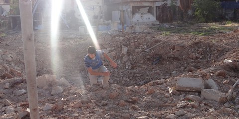 Ein Bewohner von Daraya klettert aus einem Krater, der von einer Fassbombe hinterlassen wurde (Mai 2014) © Local Council of Daraya City