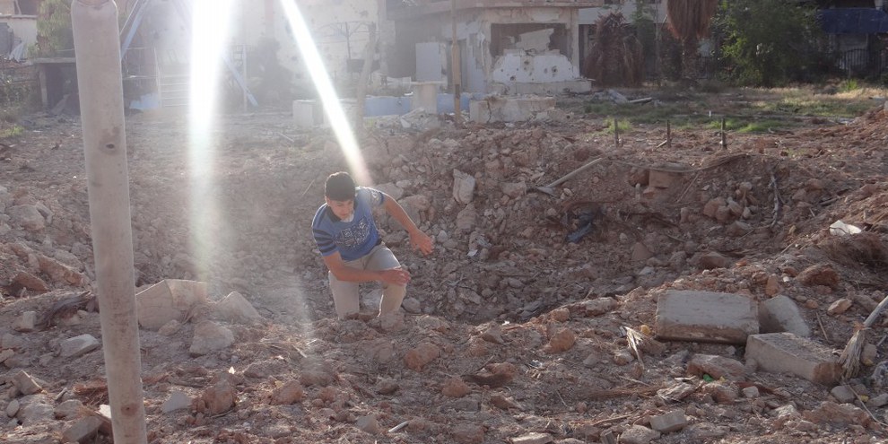 Ein Bewohner von Daraya klettert aus einem Krater, der von einer Fassbombe hinterlassen wurde (Mai 2014) © Local Council of Daraya City
