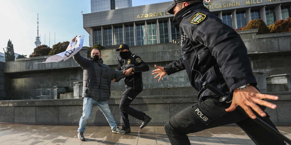 Der Direktor der Online-Publikation «Abzas Media» Ulvi Hasanli ist zu sehen, als die Polizei bei einer Kundgebung von Journalist*innen ein Plakat mit der Aufschrift «Journalismus ist kein Verbrechen» beschlagnahmt. (Baku/Aserbaidschan 28.12.2024) © Aziz Karimov/Getty Images