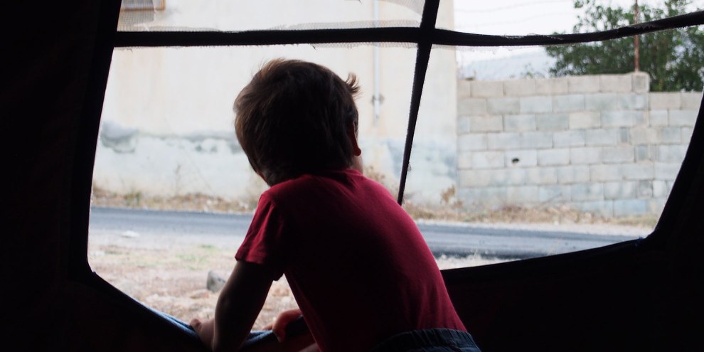 Ein Kind schaut aus einem Zelt bei Killis © Amnesty International