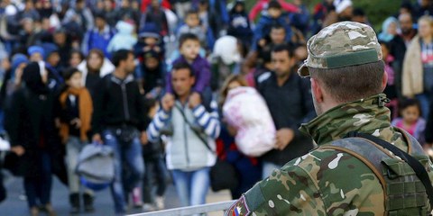 Ein Mitglied der slowenischen Armee beobachtet Migrantinnen und Asylsuchende an der österreichischen Grenze. © Leonhard Foeger/REUTERS