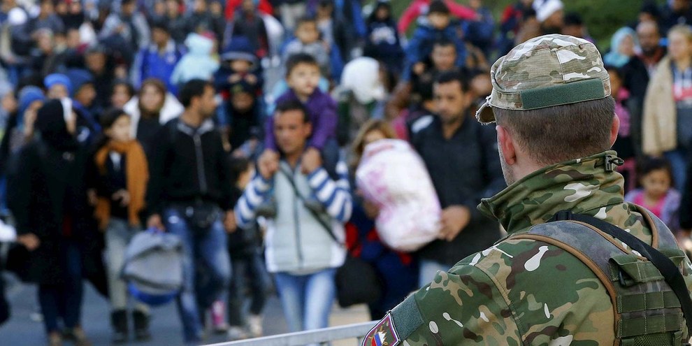 Ein Mitglied der slowenischen Armee beobachtet Migrantinnen und Asylsuchende an der österreichischen Grenze. © Leonhard Foeger/REUTERS