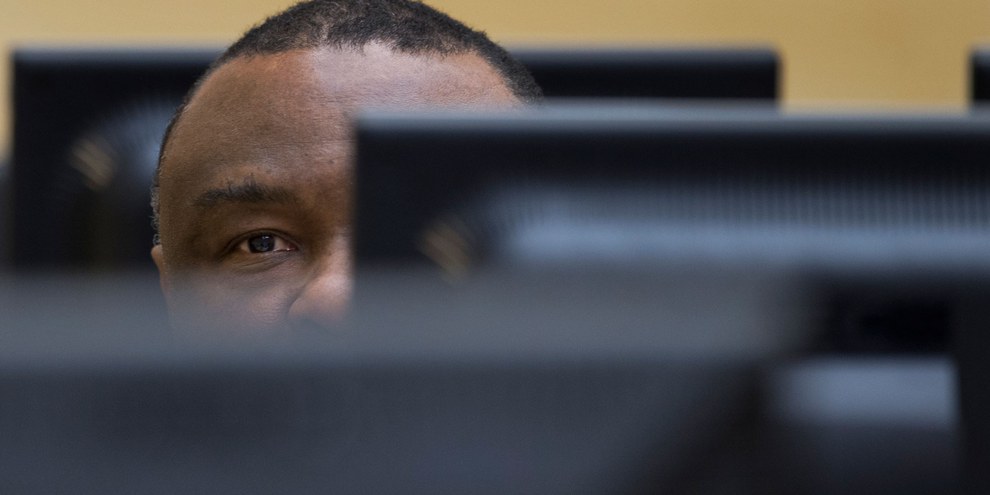 Den Haag, 27. November 2013: Der ehemalige kongolesische Präsident Jean-Pierre Bemba verbirgt zu Beginn seines Prozesses am ICC sein Gesicht vor den Reportern und Prozessbeobachterinnen. © Peter Dejong / AP Pool