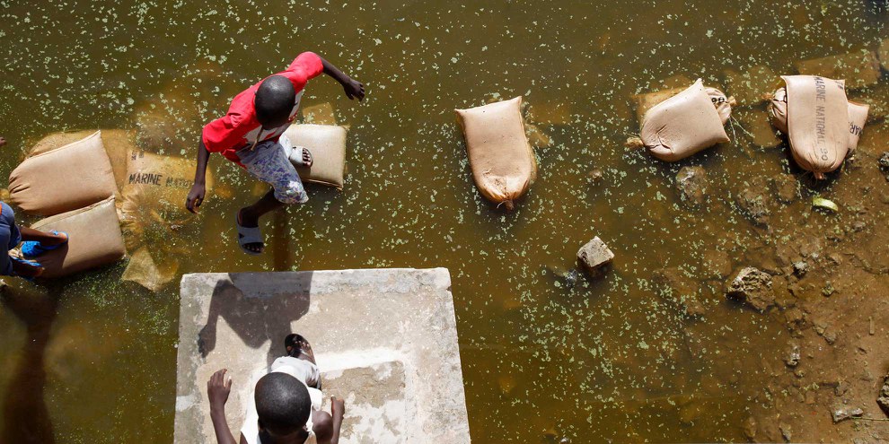 Ein Laufsteg aus Sandsäcken: Nach starken Regenfällen in einem Vorort von Dakar behilft sich die Bevölkerung mit Notlösungen. © Keystone/AP/Rebecca Blackwell