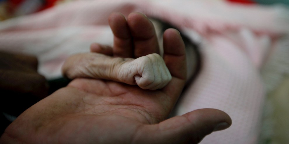 Ein Vater trauert um seine soeben an Unterernährung verstorbene Tochter, die nur vier Monate alt wurde. © Mohamed Al-Sayaghi / Reuters