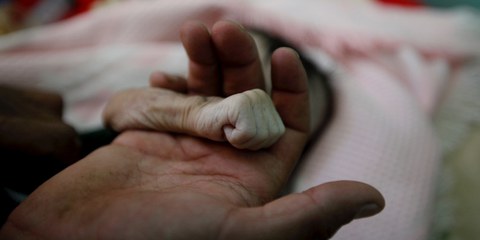 Ein Vater trauert um seine soeben an Unterernährung verstorbene Tochter, die nur vier Monate alt wurde. © Mohamed Al-Sayaghi / Reuters