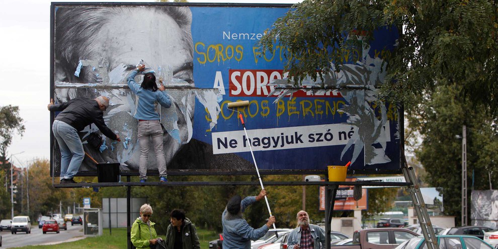 Aktivisten entfernen ein Plakat, auf dem George Soros beschuldigt wird, eine Million MigrantInnen pro Jahr in Europa ansiedeln zu wollen. © REUTERS/Bernadett Szabo