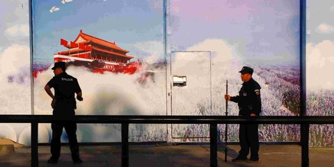 Sicherheitskräfte vor einer Einrichtung, die offiziell als «Berufsbildungszentrum» gilt, im Bezirk Huocheng in Xinjiang. Die hohen Zäune des Zentrums sind mit Propaganda-Bannern versehen, das Eingangstor mit grossen Fotopostern. © REUTERS/Thomas Peter