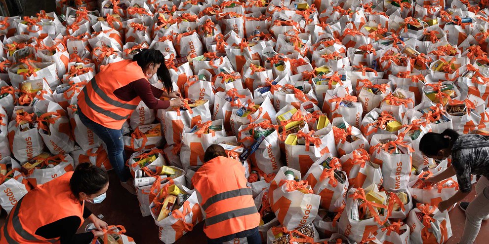 Freiwillige beim Vorbereiten der mit Lebensmitteln gefüllten Taschen. Genf im Mai 2020. Weitere Eindrücke von den Verteilaktionen bei Klick aufs Bild. © Fabrice Coffrini/AFP via Getty Images