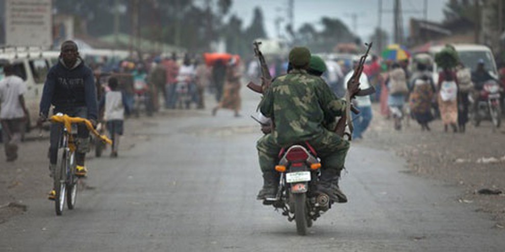 Un soldat des FARDC portant deux fusils AK-47 dans le village de Sake, Nord Kivu, tandis que la population fuit à cause des affrontements des FARDC avec les groupes rebelles, 30 avril 2012. © Blattman