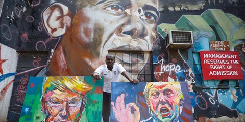 L’artiste kenyan Yegonizer et ses portraits de Donald Trump, devant une oeuvre murale de Bankslave représentant Obama. © Keystone/EPA/DAI KUROKAWA