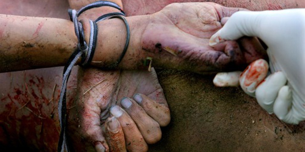 Un officier examine les mains attachées d’un homme assassiné. Guatemala City, 2005. © AP/PA Photo/Rodrigo Abd 
