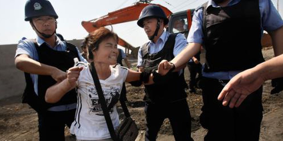 Des gens obligés de quitter leur foyer sont brutalisés par la police. © Fang Xinwu / Color China Photo / AP Photo