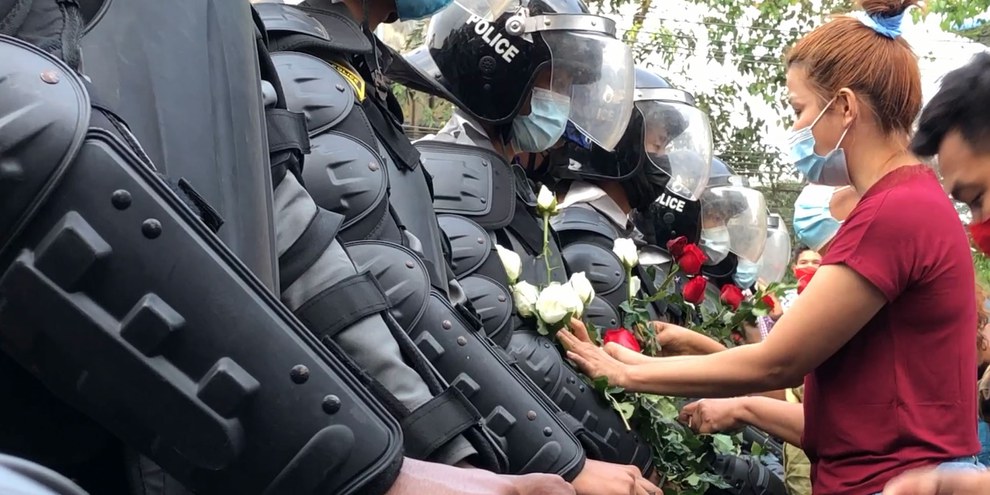 Des activistes offrent des fleurs aux forces de la police, lors d'une manifestation à Yangon © Maung Sun / wikimedia