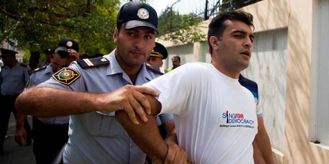 Des policiers arrêtent le défenseur des droits humains Rasul Jafarov. Il s’était engagé pour la démocratie dans son pays. Bakou, juin 2014. © RFE