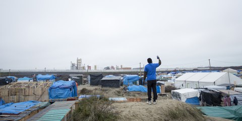 Un résident de la «Jungle» à Calais cherchant un signal réseau sur son téléphone.  © Richard Burton/Amnesty International