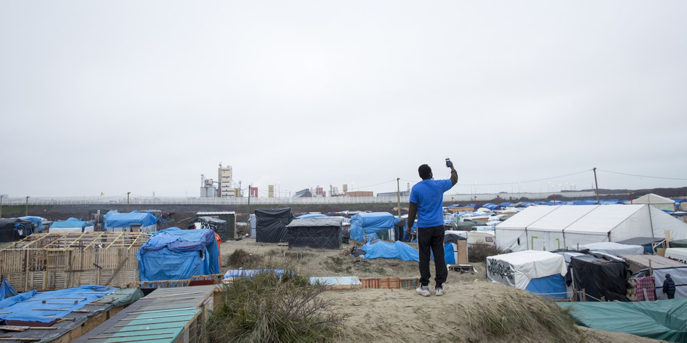 Un résident de la «Jungle» à Calais cherchant un signal réseau sur son téléphone.  © Richard Burton/Amnesty International