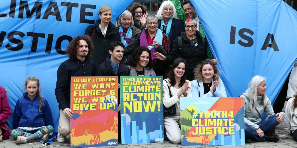 Des activistes pour le climat attendaient avec des pancartes la décision de la Cour européenne des droits de l'homme dans trois affaires climatiques différentes, le 9 avril 2024 à Strasbourg. © AFP via Getty Images