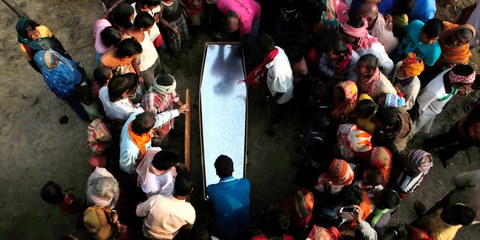 Dans un village népalais, des proches et habitant·e·x·s se rassemblent autour du cercueil d'un travailleur migrant, décédé dans son sommeil au Qatar. © Niranjan Shrestha/AP/Shutterstock