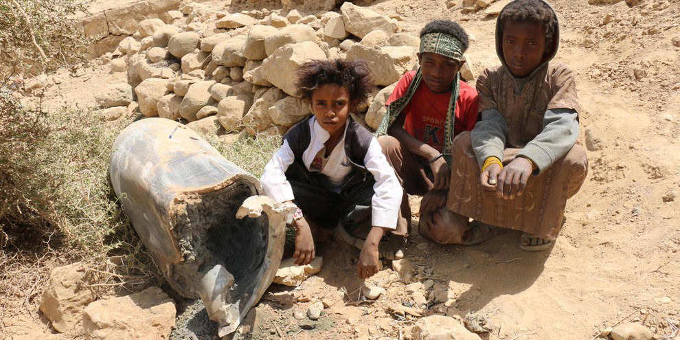Des enfants dans la ville de Saada au Yémen assis à côté d'un obus. © Amnesty International