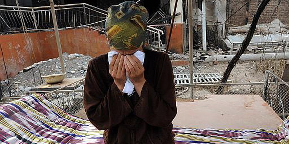 Après les troubles meurtriers, une femme dans les décombres de ses propriétés familiales. © UNHCR/S. Schulmann 