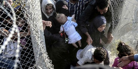 Des Syrien·ne·s profitent de trous dans les barbelés pour entrer illégalement en Turquie à la frontière d'Alçakale, le 14 juin 2015. © Bülent Kiliç - AFP/Getty Images
