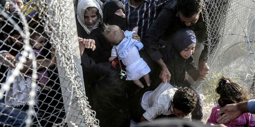 Des Syrien·ne·s profitent de trous dans les barbelés pour entrer illégalement en Turquie à la frontière d'Alçakale, le 14 juin 2015. © Bülent Kiliç - AFP/Getty Images