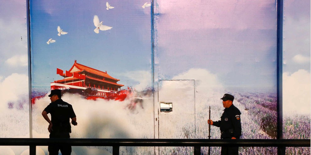 Les forces de sécurité devant une institution officiellement classée "centre de formation professionnelle" dans le district de Huocheng au Xinjiang. Les hautes clôtures du centre sont équipées de bannières de propagande, le portail d'entrée de grandes affiches photo. © REUTERS/Thomas Peter