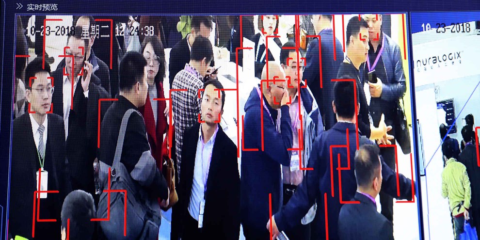 Sur cette photo prise le mardi 23 octobre 2018 à l'exposition Security China 2018 à Pékin, le public est observé par la technologie de reconnaissance faciale du fabricant public d'équipement de surveillance Hikvision. © AP Photo/Ng Han Guan