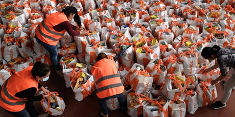 Des bénévoles s’activent lors d’une distribution de colis d’hygiène et de nourriture aux Vernets, à Genève. La crise du coronavirus a fragilisé une partie de la population qui s’est retrouvée en grande difficulté du jour au lendemain. En deux mois, près de 16 000 sacs ont été distribués. ©Getty Images / Fabrice Coffrini