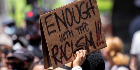 Un manifestant brandit un panneau « Assez de racisme » devant la Trump Tour, à New York, lors de la Black Womxn’s Empowerment March (une marche pour l‘émancipation des femmes noires) du 12 juin 2020. ©Ira L. Black / Corbis via Getty Images