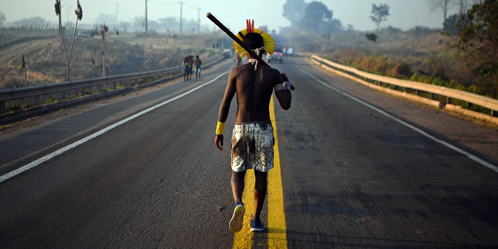 Un membre de la communauté Kayapo marche au milieu de l’autoroute BR163 durant une manifestation à Novo Progresso, au nord du Brésil, le 17 août 2020. Des activistes autochtones ont protesté contre le manque de soutien gouvernemental pendant la pandémie du COVID-19, et pour dénoncer la déforestation illégale sur leurs territoires. © CARL DE SOUZA/AFP/Getty Images