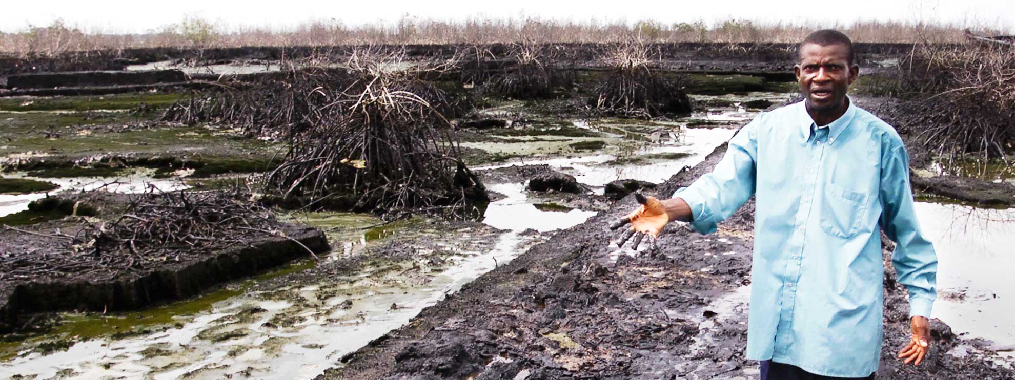 Christian Lekoya Kpandei montre les dégâts que les fuites de pétrole ont fait sur son champ. © Amnesty International