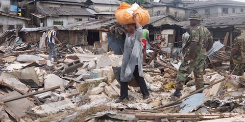 Un homme porte ce qu’il a pu sauver de chez lui après la démolition de son logement. Quartier d’Abonnema Wharf, 27 juin 2012. © DR 