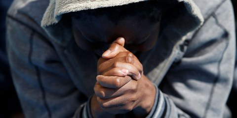 Un uomo prega dopo esser stato soccorso dalla nave Topaz dell’organizzazione di aiuto private MOAS (Migrant Offshore Aid Station) a 20 miglia nautiche dalla costa libica, 23 giugno 2016. © REUTERS/Darrin Zammit Lupi