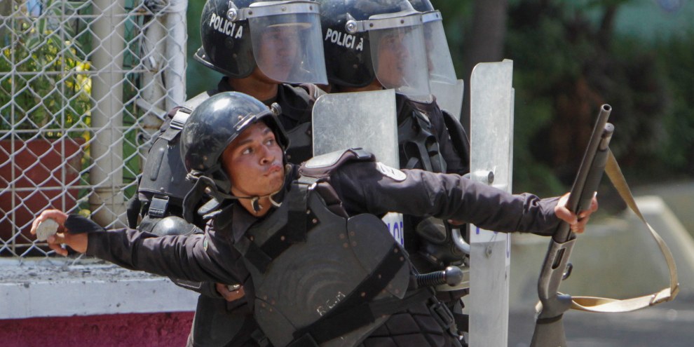 Managua, 19 aprile 2018 : un poliziotto lancia una pietra contro gli studenti che protestano davanti all’Università. © Inti Ocon/AFP/Getty Images
